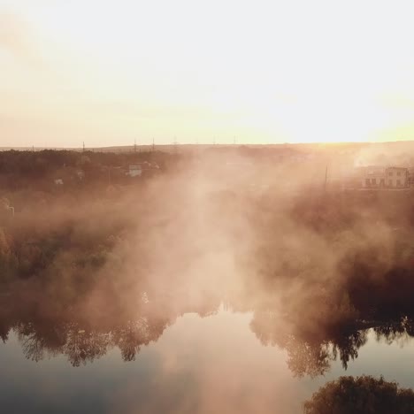 smoke from the fire are spreading over the river at sunset on the background of a power station with two pipes. aerial view