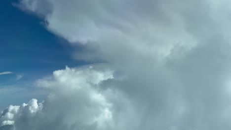 aerial view taken from a jet cockpit flying at cruise level near a cumulus with a deep blue sky in a splendid atumn morning