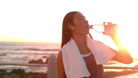 pretty woman drinking water after jogging