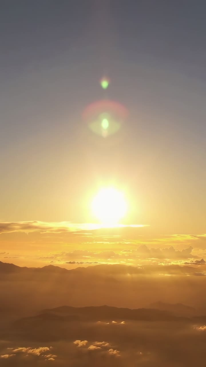 Gylden solnedgang over skyer og bjergtoppe