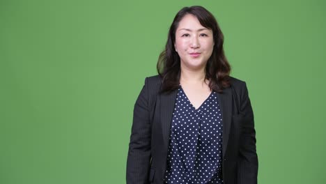 성숙하고 아름다운 아시아 사업가 여성이 무언가를 보여주고 있습니다.