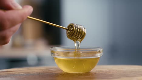 close up of honey dripping from honey dipper.