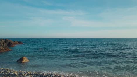 drone sobre el océano, moviéndose hacia atrás lentamente hacia la playa