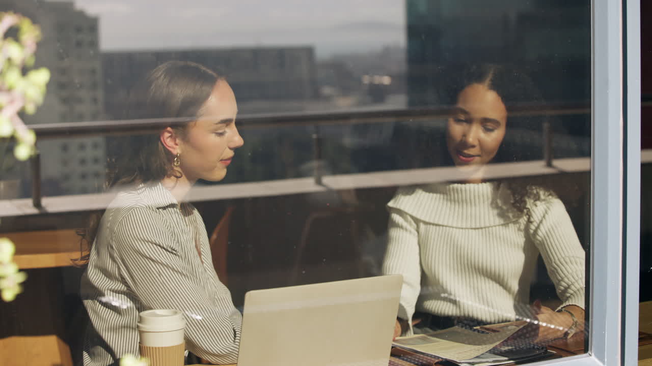 Two business women working in cafe
