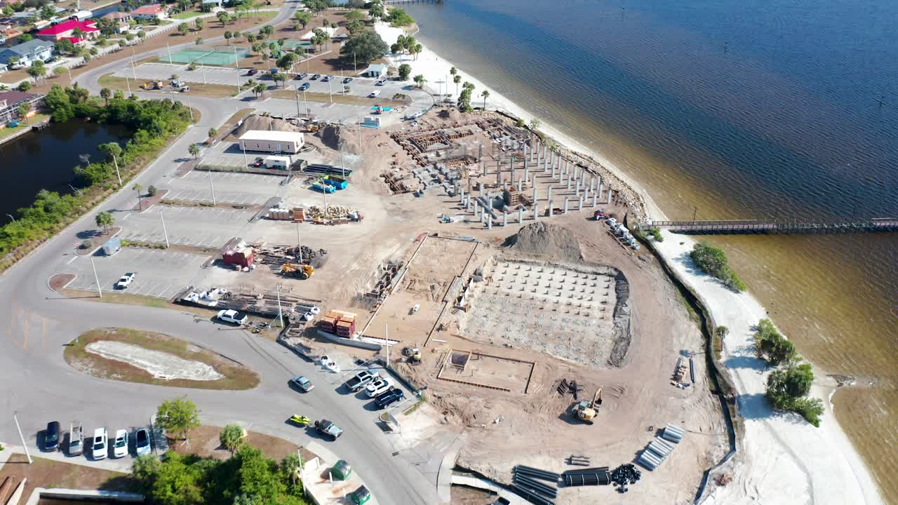 Zona costera en Gulf Breeze, Florida, con playas de arena, muelles, aparcamientos y obras cerca de barrios residenciales junto a la bahía.