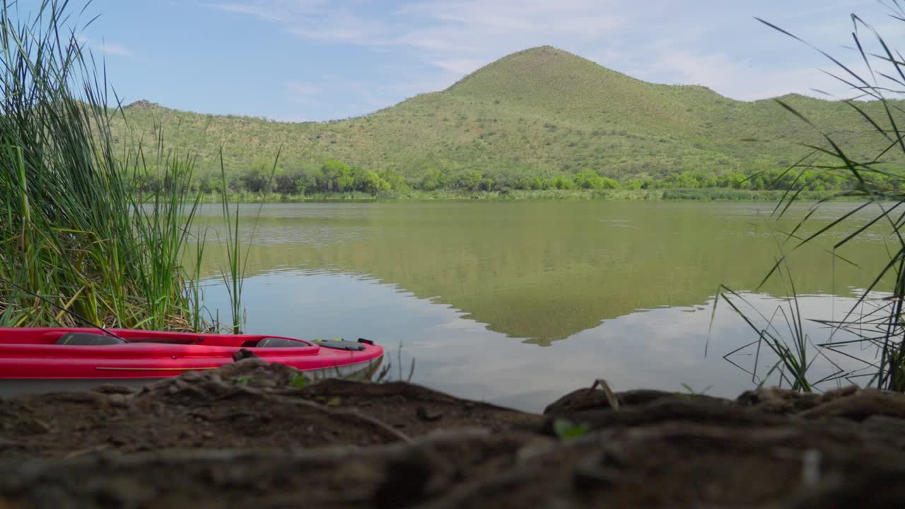 zoom lento y suave sobre el lago patagonia, con montañas en el fondo y una canoa roja en primer plano