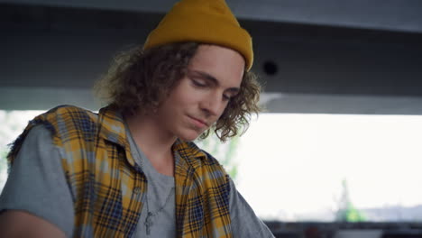 smiling teen resting after training on bmx bike at skate park. curly hair man.