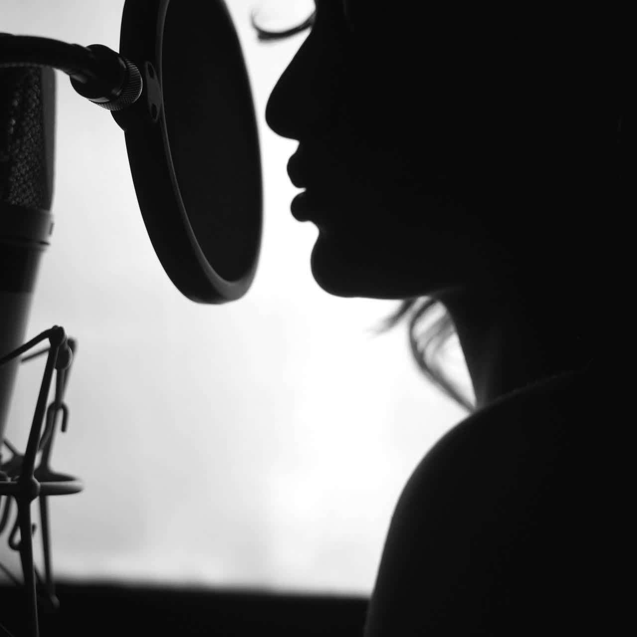 Black and White. Woman singing in the recording studio. Profile of a woman with a beautiful face and lips. Square video