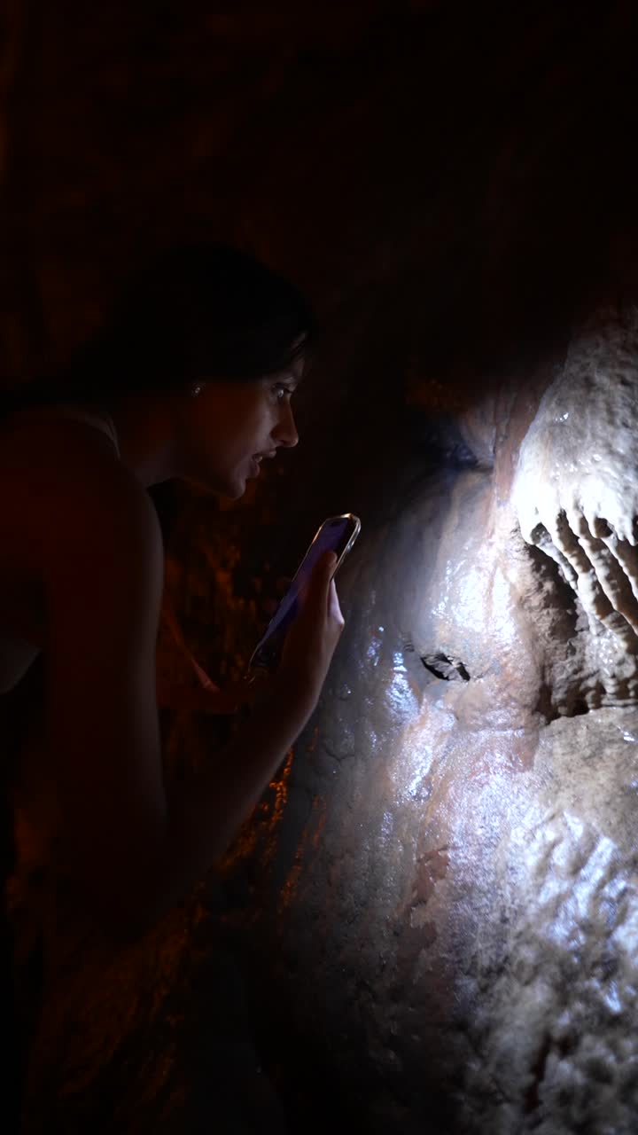 Woman exploring a cave with a smartphone