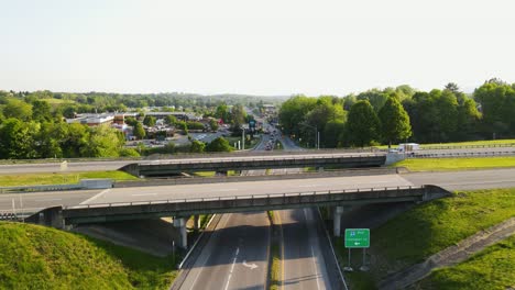 Aerial-push-in-shot-of-ambulance-crossing-highway-bridge-with-emergency-lights-on-with-city-in-the-background-during-summer