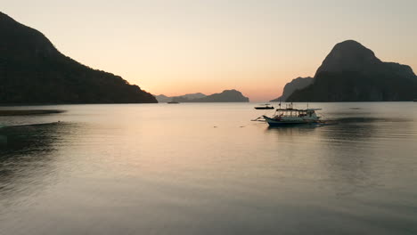 Antena-Que-Muestra-Un-Barco-Estabilizador-Y-La-Isla-Cadlao-Con-Puesta-De-Sol-Y-Hora-Dorada-En-El-Nido,-Palawan,-Filipinas