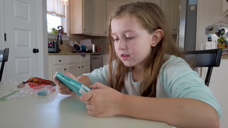 A-young-girl-plays-video-games-at-a-kitchen-table