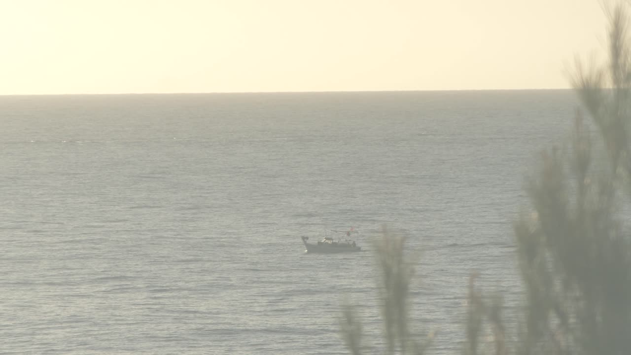 A fishing boat sailing across the bay in early morning light