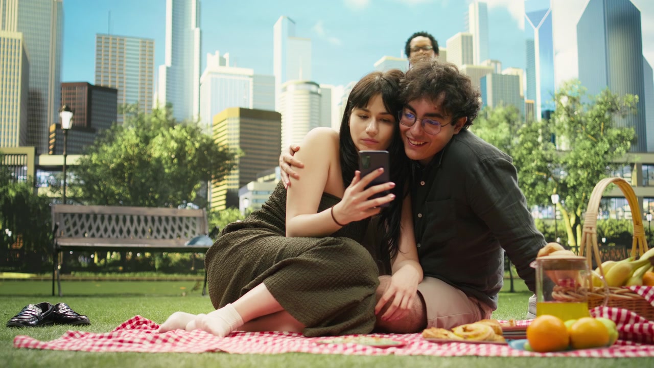 Young woman holding smartphone for partner as they watch funny video content