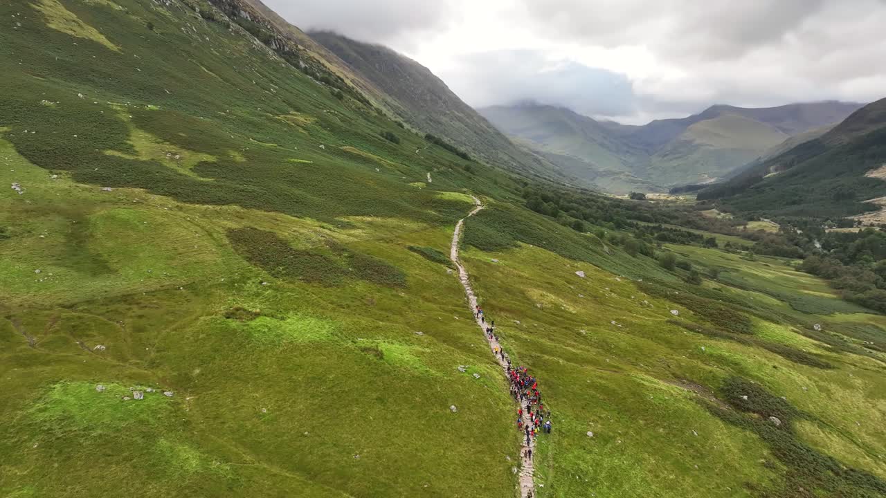 Aerial footage of hill walkers starting climb to Ben Nevis, Drone shot of valley in Glen Nevis, Fort William