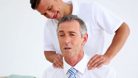 physiotherapist giving stressed businessman a shoulder massage