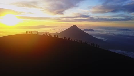 group of people standing on top of a volcano in the sunrise