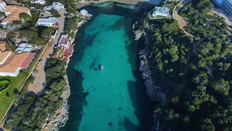 Luxury-super-yacht-mooring-in-small-harbour-of-Sa-Caleta,-Menorca-Spain