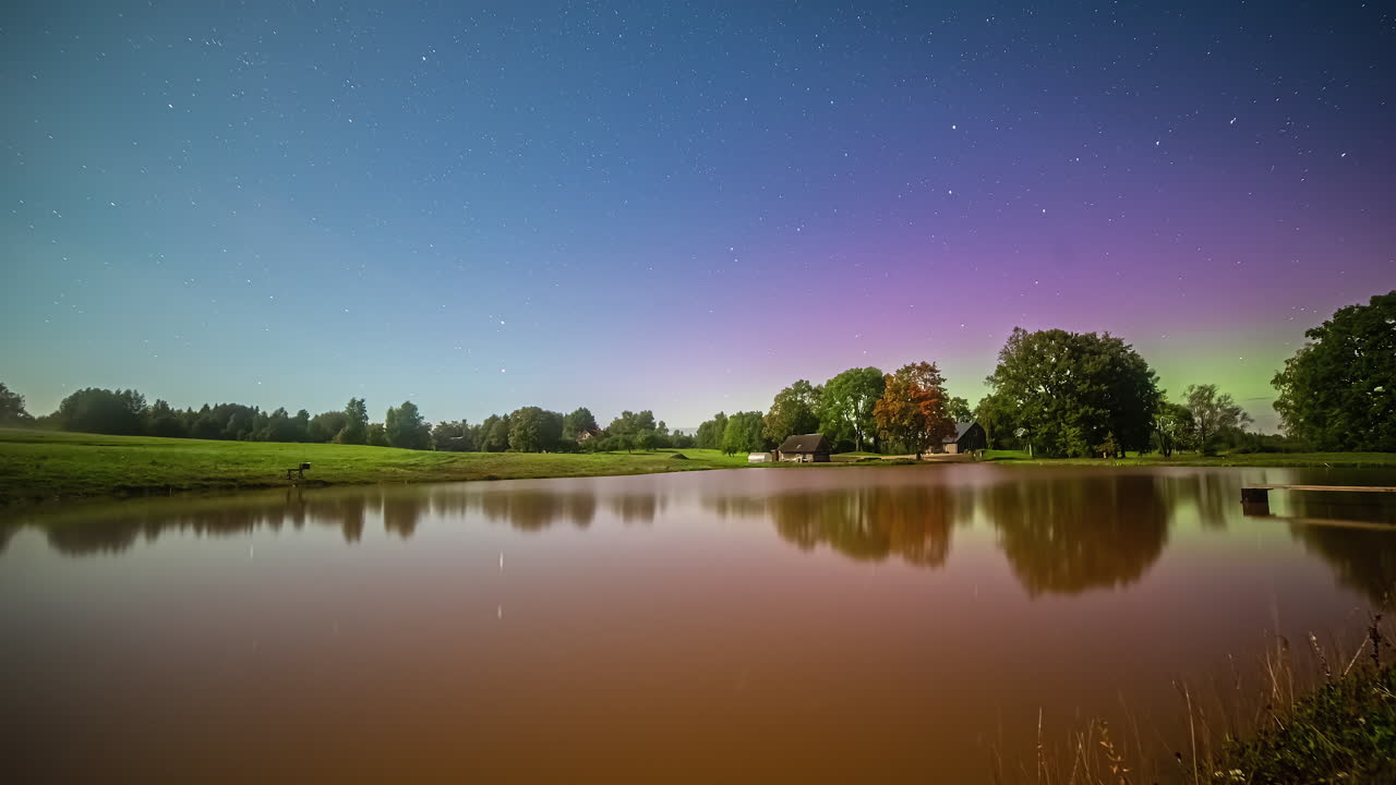 la aurora boreal aparece por encima de la superficie del agua tranquila más tarde, vista de lapso de tiempo