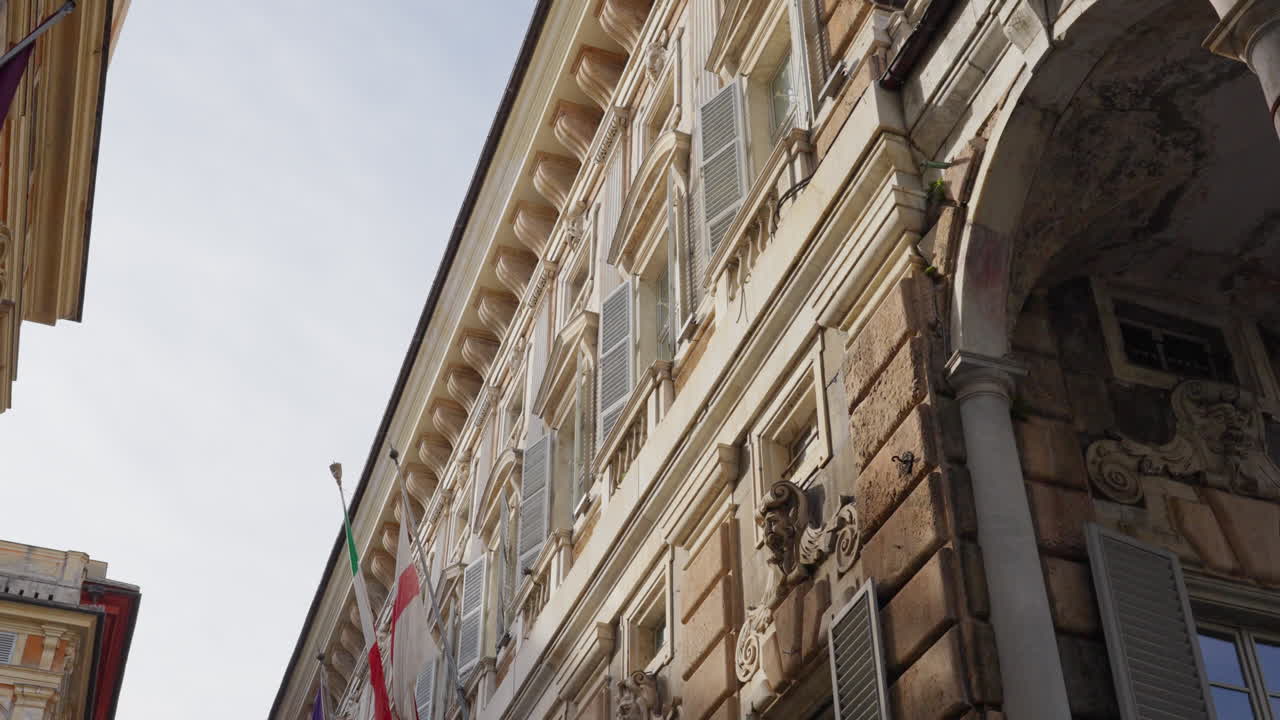 Vista dal basso di un edificio amministrativo storico a Genova, Italia, con bandiera nazionale.