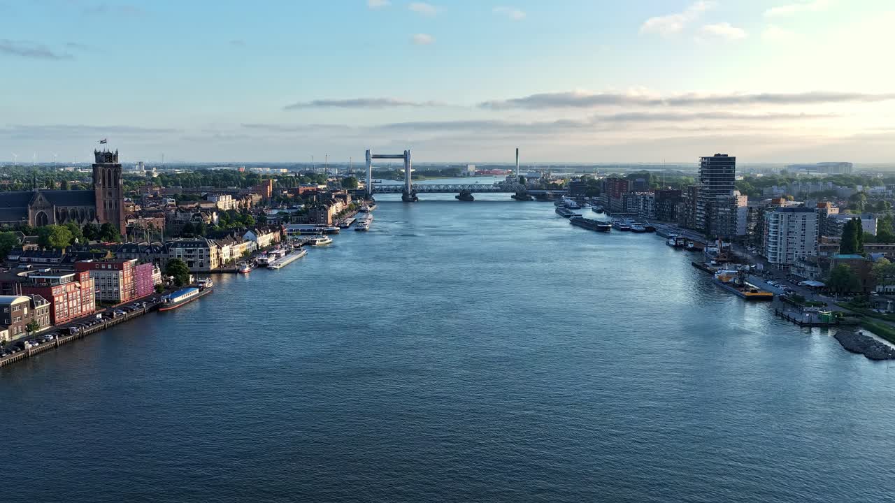 A drone hyperlapse moves above Dordrecht, showing boats on the canal and the city skyline under clear morning light