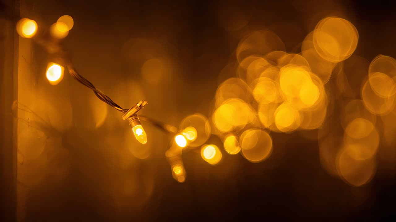 Shifting camera focus to reveal twisted wire, plastic housings on warm-white LED string in dim room