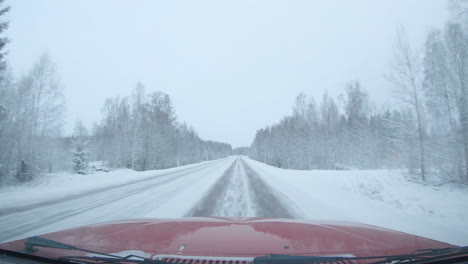 Windscreen-view,-the-car-drives-fast-down-a-snowy-main-road-on-an-overcast-day