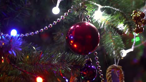 Rack-focus-on-red-Christmas-bulb-on-brightly-illuminated-Christmas-tree