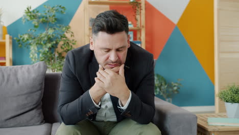 man sitting on a couch looking depressed