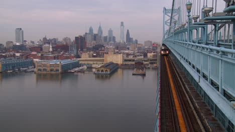 a commuter train crosses the ben franklin bridge with philadelphia pa in background