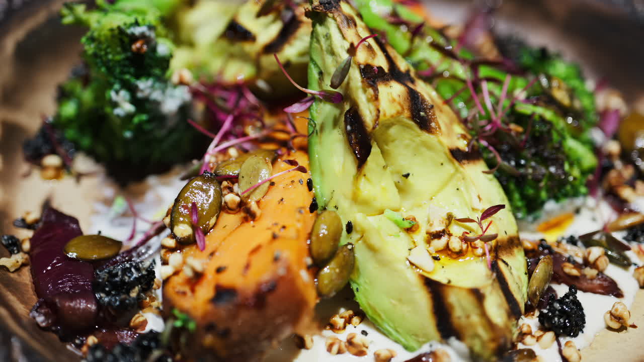 Close up of a salad with grilled avocado, sweet potato and broccoli on a plate at a restaurant