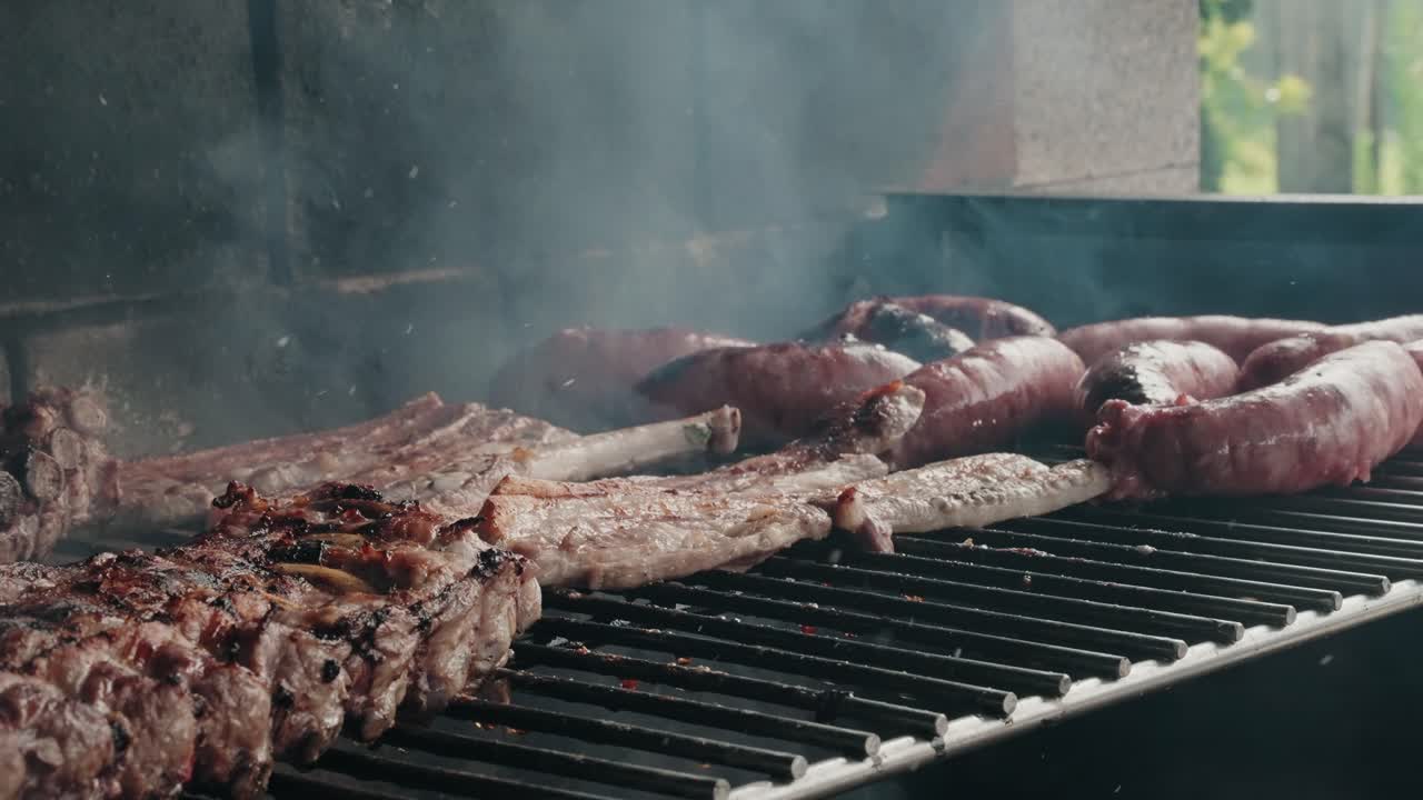 Close up smoky barbecue grill cooking sizzling sausages and pork ribs outdoors