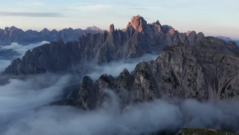 mysteriöse sonnenaufgangsdrohnenaufnahme von wolken, die die bergkette cadini di misurina in den dolomiten, italien, bedecken