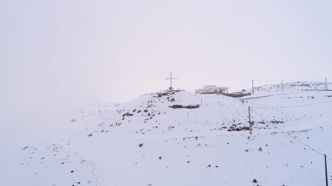 aerial christian cross on a peak in the high snowy mountains