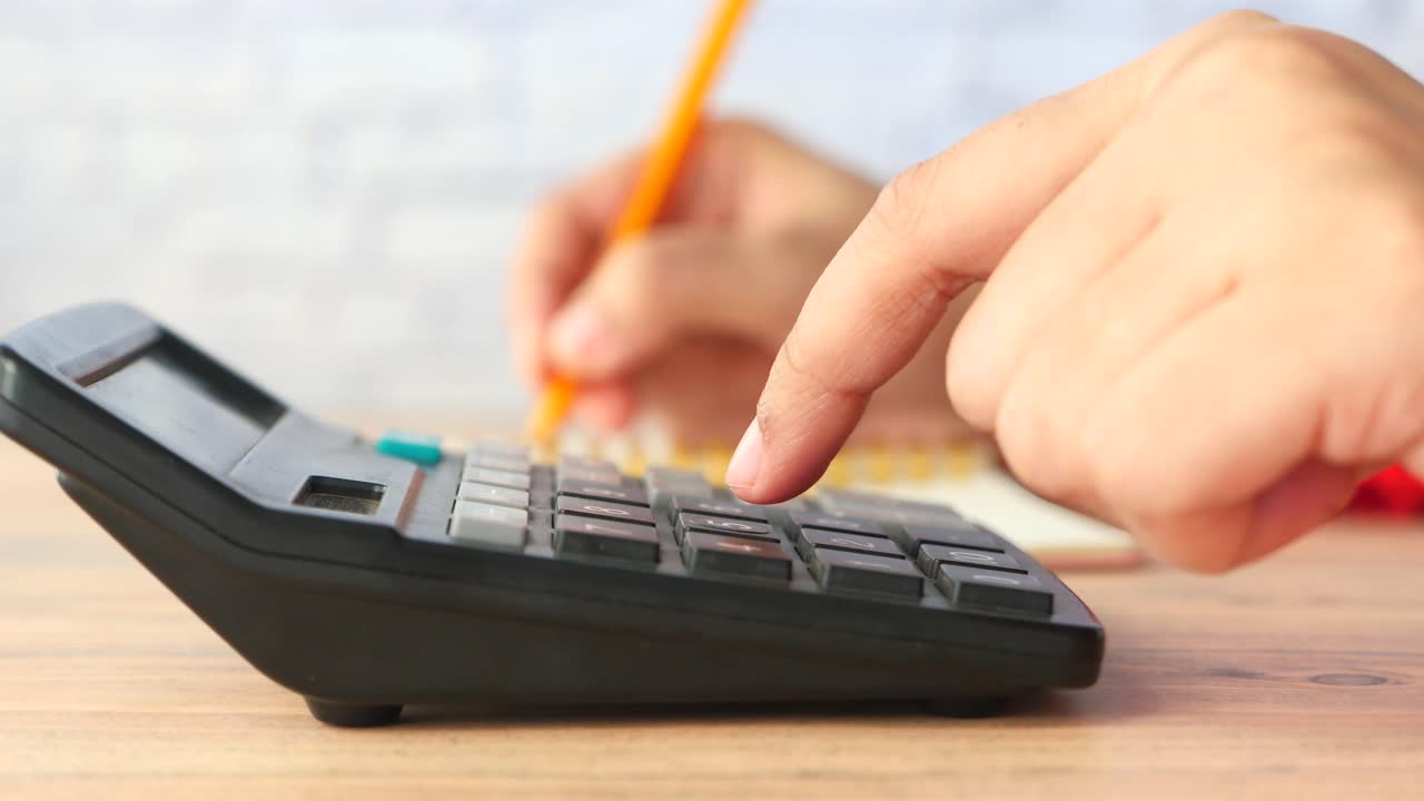 persona que utiliza una calculadora y un bolígrafo
