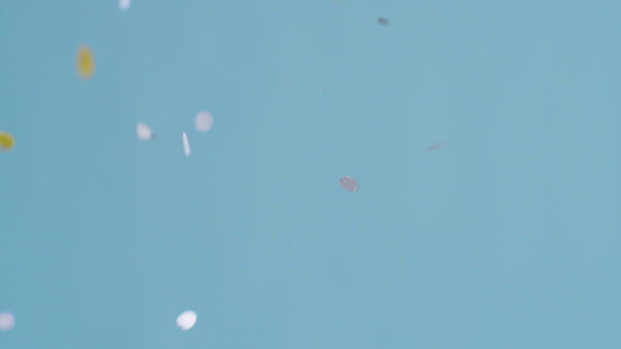 파란색 배경에 떨어지는 회색 및 금색 색종이의 고정 샷