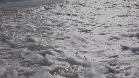 shot-of-the-shore-of-the-beautiful-juan-dolio-beach-at-sunset,-waves-moving-on-the-warm-sand,-beautiful-detail-in-slow-motion