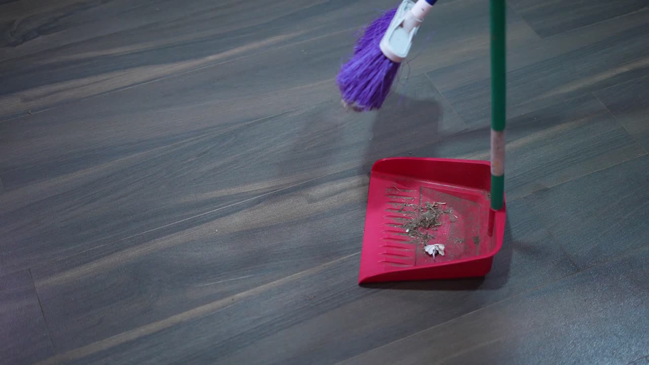 집 먼지를 모으는 빗자루와 쓰레받기로 집 바닥을 쓸다