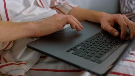 hombre de primer plano usando touchpad en la oficina de casa. gerente desconocido trabajando en pijama
