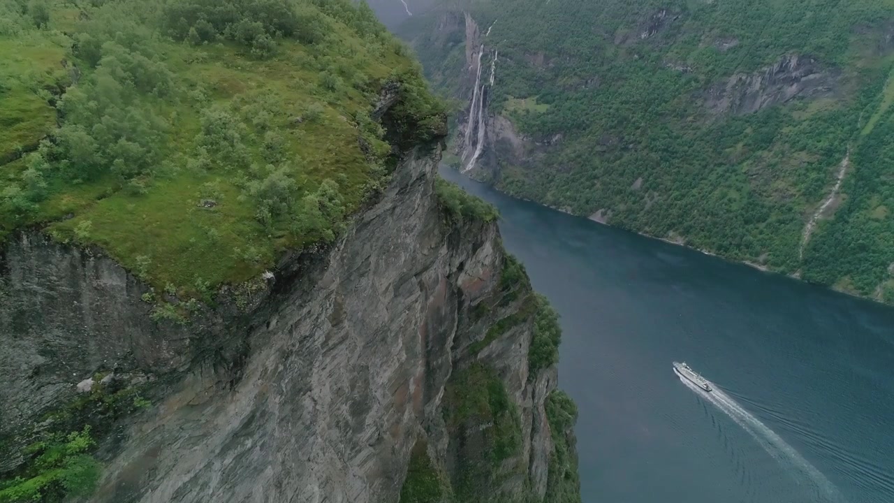 Zwolnione tempo z lotu ptaka Fiordu Geiranger z płynącą łodzią i wodospadem Siedem Sióstr w tle.