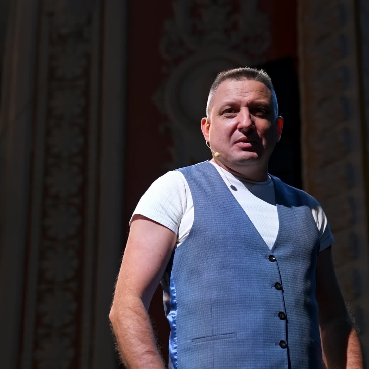 Man in suit speaking jokes in micropphone standing on stage. Funny performance. Comedian in good humor speaks to the audience