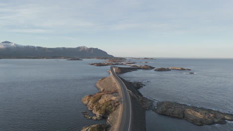 upwards drone shot flying over the famous bridges over the atlantic ocean road or atlanterhavsvegen in hustadvika norway in the morning during sunrise with cars traveling underneath log