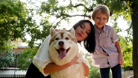 familia y mascota, mujer abrazando a un perro husky en primer plano en el fondo de la naturaleza y el niño