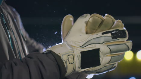 close-up of gloved hands clapping together, showcasing detailed stitching and textured padding under soft night lighting, background features blurred bokeh lights