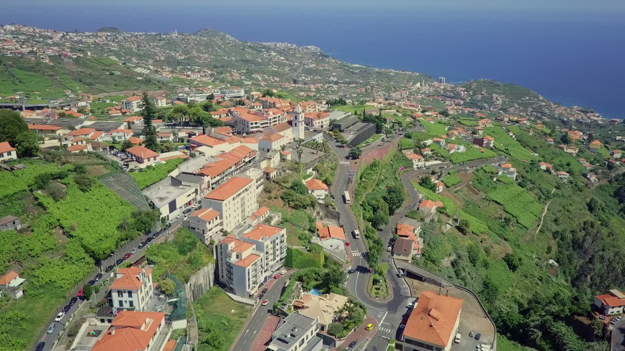 Imagem aérea em movimento sobre uma comunidade na encosta da Madeira, Portugal, ao meio-dia.