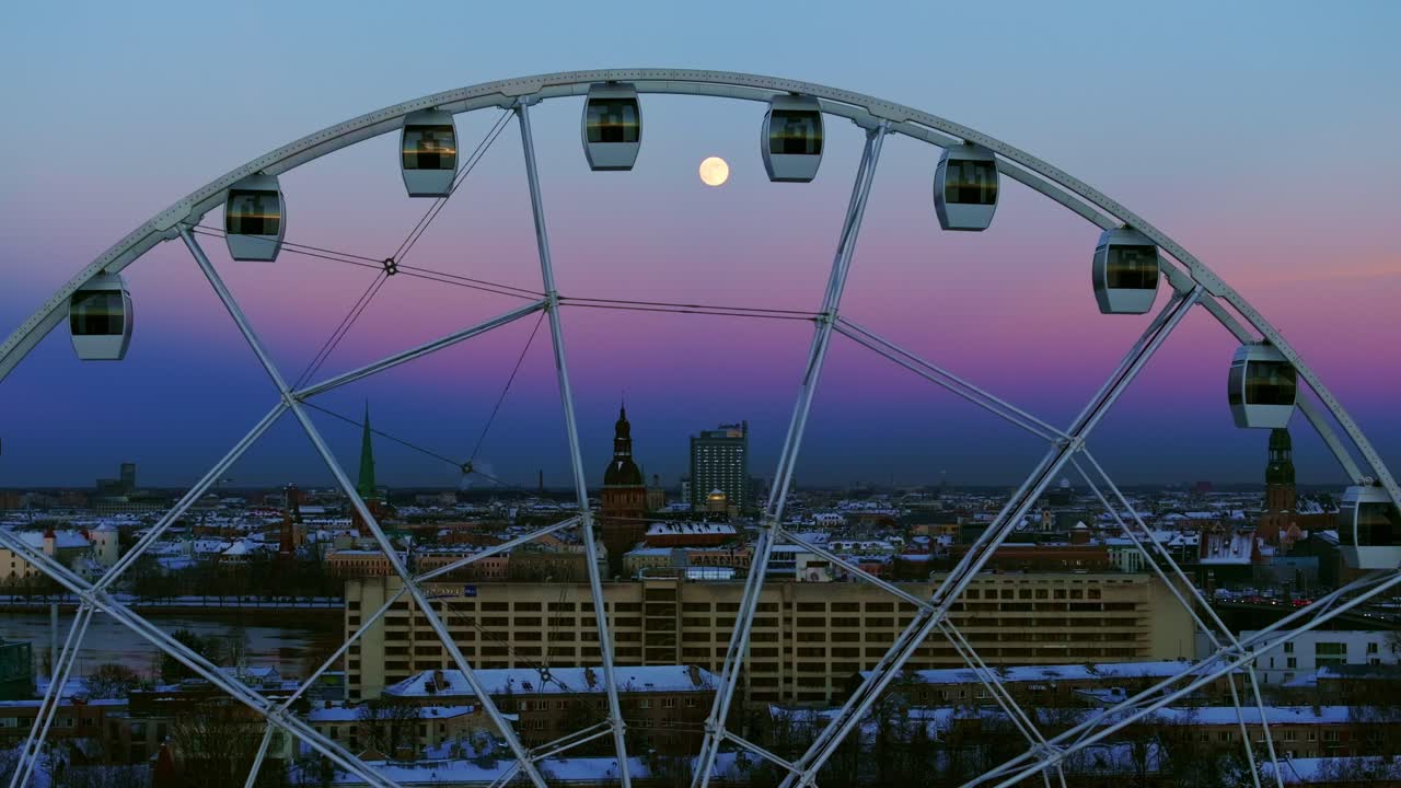 Evening tones and full moon frame Riga skyline in snowy winter drone shot