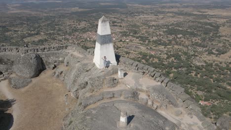 Woman-greets-drone-from-fortification-of-Monsanto-Castle-and-walking-on-walls,-Portugal