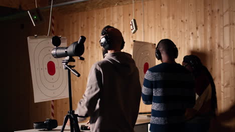 friends in firing range shooting, zooming to check points scored on bullseyes