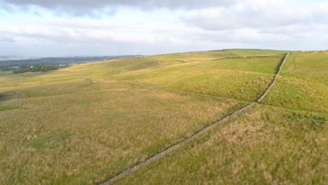 Drone-footage-in-the-evening-golden-hour-crossing-farmland-and-moorland-in-rural-West-Yorkshire,-England,-UK