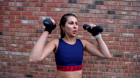 female exercising outside with dumbbells lifting weights up